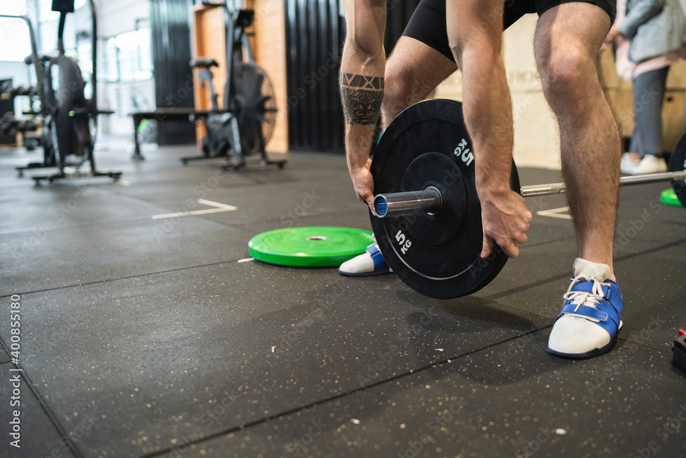 Man picking up barbell while standing in gym Man picking up barbell while standing in gym