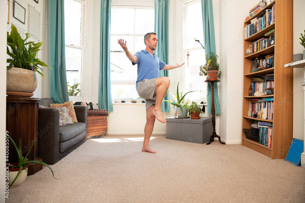 Mature man balancing on leg while standing at home Mature man balancing on leg while standing at home