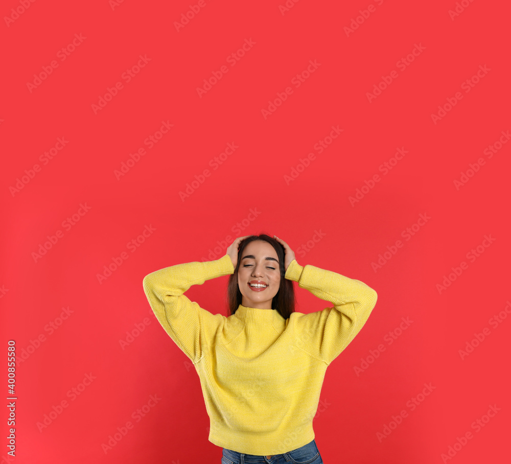 Beautiful young woman wearing yellow warm sweater on red background Beautiful young woman wearing yellow warm sweater on red background