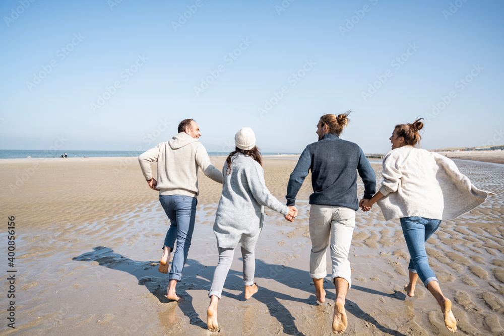 Family holding hands while running on beach Family holding hands while running on beach