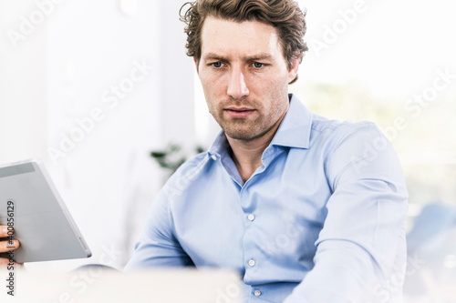 Man concentrating while using digital tablet sitting in office