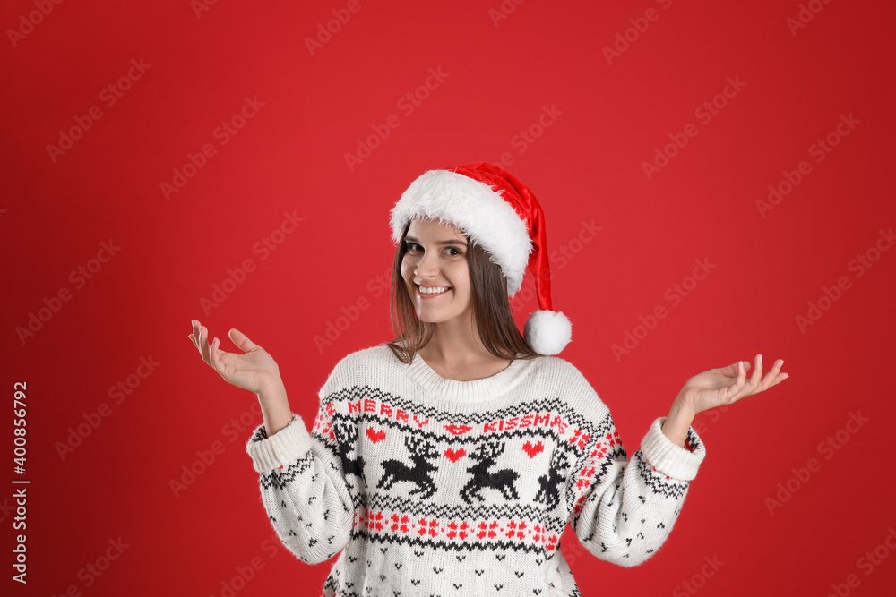 Pretty woman in Santa hat and Christmas sweater on red background Pretty woman in Santa hat and Christmas sweater on red background