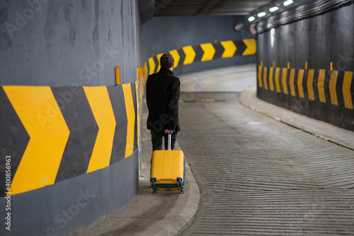 Man with a rolling suitcase in a parking. Man in underground car parking garage