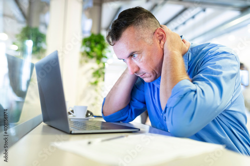 Distressed businessman staring at laptop while sitting in coffee shop