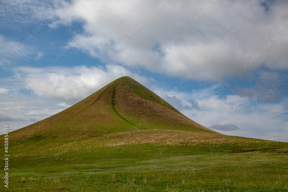 A solitary mountain covered with young, green grass. A country road leads to the top. Plenty of free space to insert.