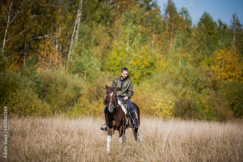 Cute girl-rider rides her fast horse on the territory of the ranch.