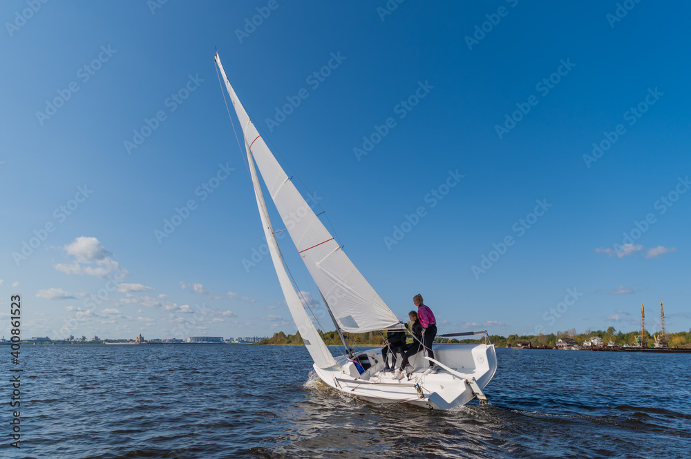 Obraz premium A mixed crew of a sports yacht participates in sailing competitions on the river. One man and two girls