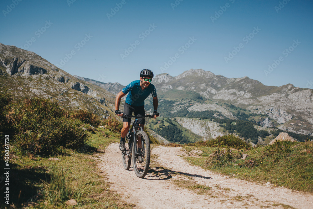 Male cyclist riding mountain bike on trail against sky, Picos de Europa National Park, Asturias, Spain Male cyclist riding mountain bike on trail against sky, Picos de Europa National Park, Asturias, Spain