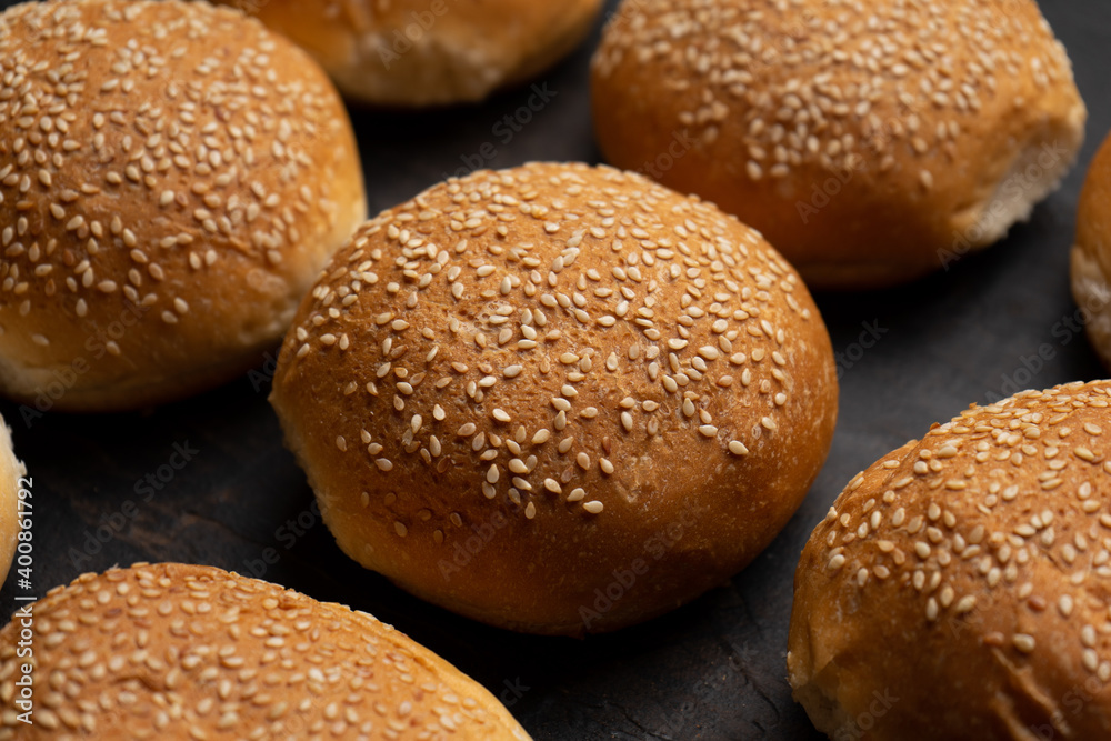 Burger bun bread with sesame seeds on dark background Burger bun bread with sesame seeds on dark background