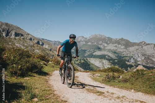 Male cyclist riding mountain bike on trail against sky, Picos de Europa National Park, Asturias, Spain