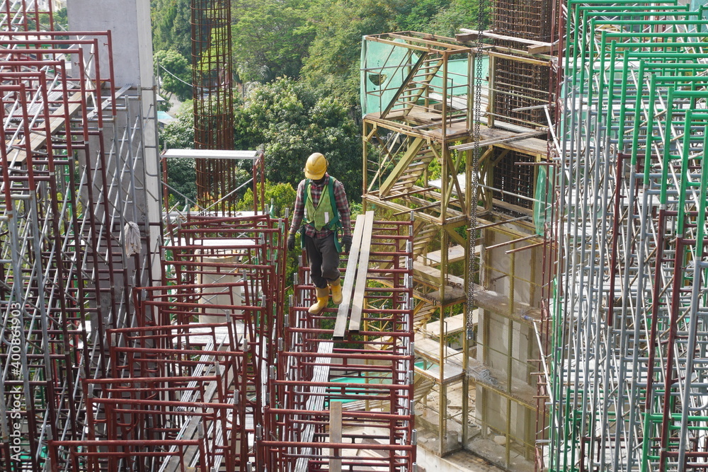 MALACCA, MALAYSIA -MARCH 14, 2020: Construction workers working at height at the construction site. They are supplied with harnesses and other safety equipment to prevent them from having an accident.