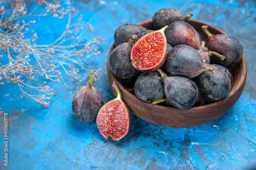 Fototapeta Naklejka Na Ścianę i Meble -  Front close view of fresh black mission figs in a small brown pot on blue background