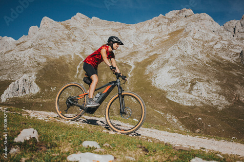 Female cyclist riding bike near rock mountain at Picos de Europa National Park, Cantabria, Spain photo