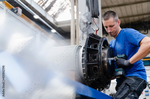 Male technician fastening bolt with equipment in industry