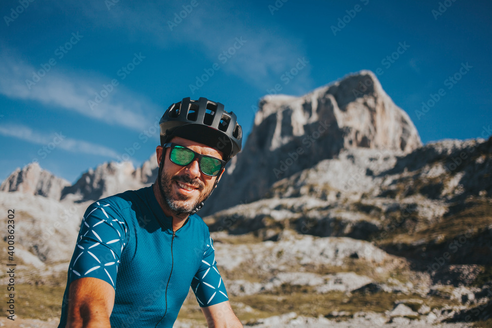 Smiling mid adult male cyclist wearing cycling helmet and sunglasses at Picos de Europa National Park, Cantabria, Spain Smiling mid adult male cyclist wearing cycling helmet and sunglasses at Picos de Europa National Park, Cantabria, Spain