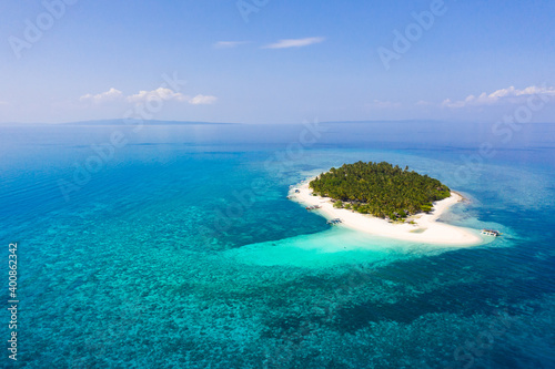 Island with a tropical beach and turquoise lagoons. Tropical island on a coral reef, top view.