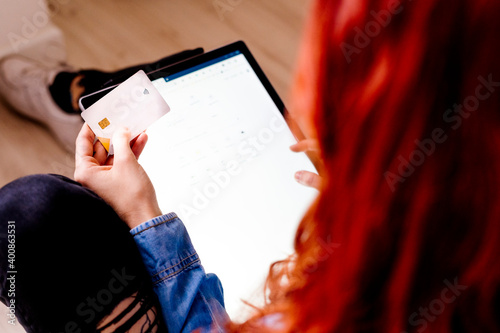 Businesswoman with credit card doing shopping on digital tablet while sitting at office