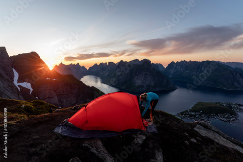 Mid adult woman building camp on mountain at Reinebringen. Lofoten, Norway photo