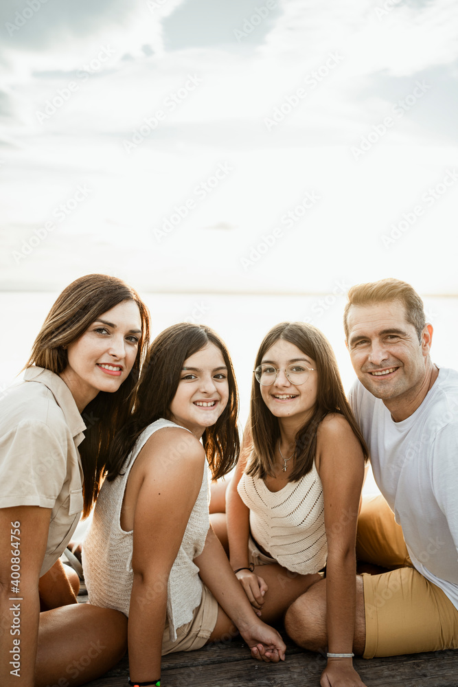 Smiling family sitting on jetty against sky Smiling family sitting on jetty against sky