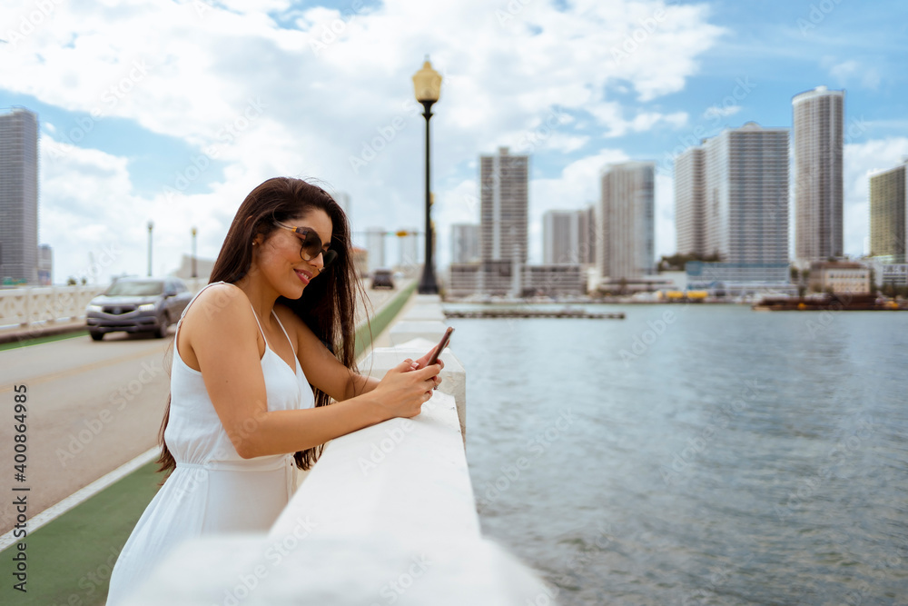 Smiling woman using mobile phone while leaning on retaining wall Smiling woman using mobile phone while leaning on retaining wall