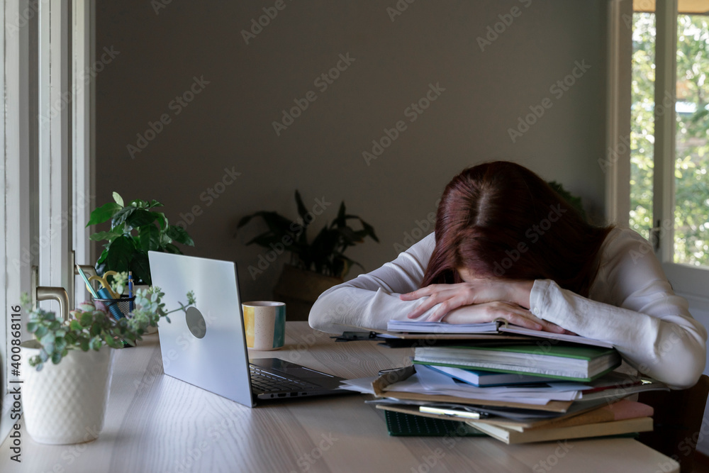 Tired doctor leaning on stack of book while sitting at home Tired doctor leaning on stack of book while sitting at home