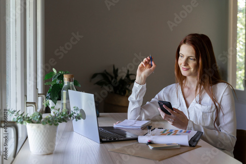 Smiling woman using mobile phone and fidget spinner while sitting at home photo