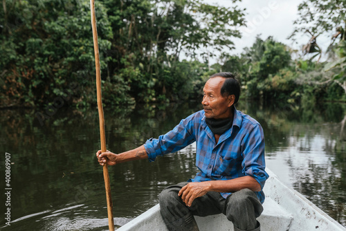 Senior Guarani man sitting in canoe at Napo River, Ecuador photo