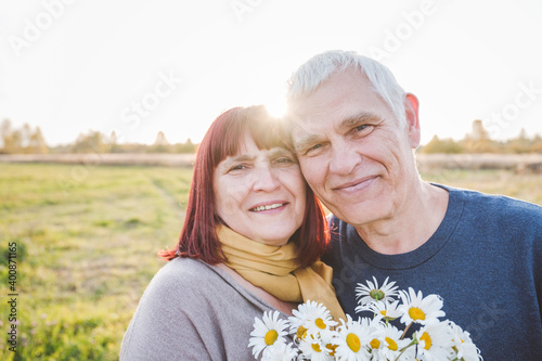 Smiling senior couple with chamomile flowers photo