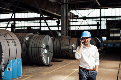 Male owner with hand in pocket talking on smart while standing at factory photo