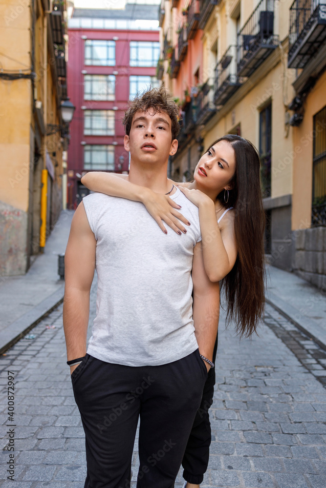 Young woman embracing man from behind while standing on footpath Young woman embracing man from behind while standing on footpath