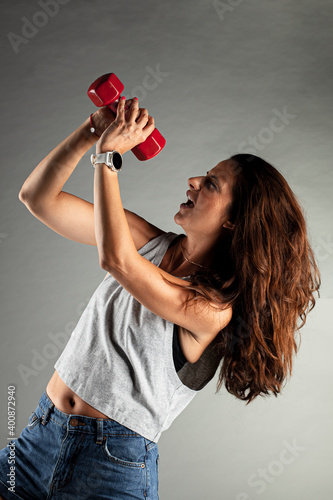 Fitness girl having fun after workout with weights. Singing and posing with red weight photo