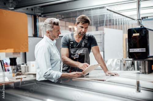 Mature worker discussing with manager over document in factory photo