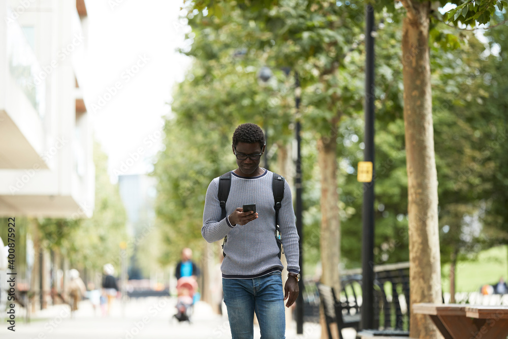 Businessman using mobile phone while walking on footpath Businessman using mobile phone while walking on footpath