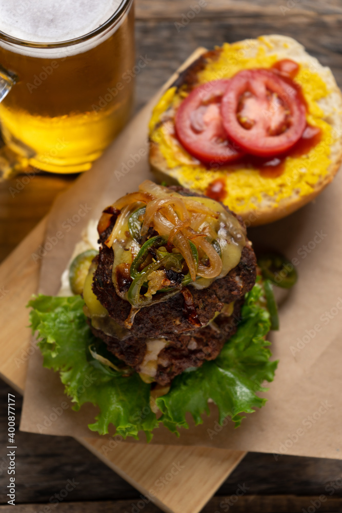 Cheese burger with caramelized onion and jalapeno pepper on wooden background