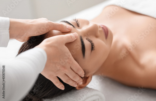 Spa therapist making relaxing head massage for beautiful asian woman in salon