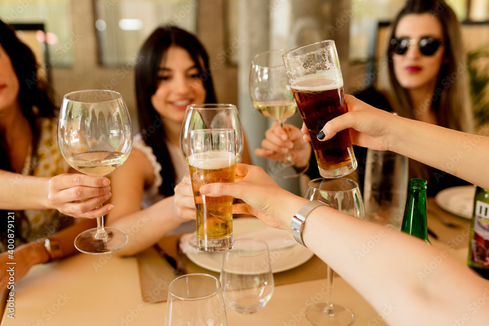 Happy female friends toasting drinks while sitting at table in restaurant