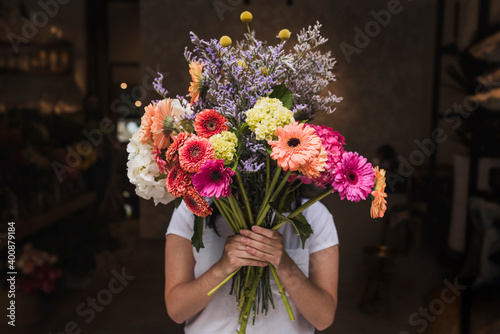 Female florist holding colorful flowers while standing in shop