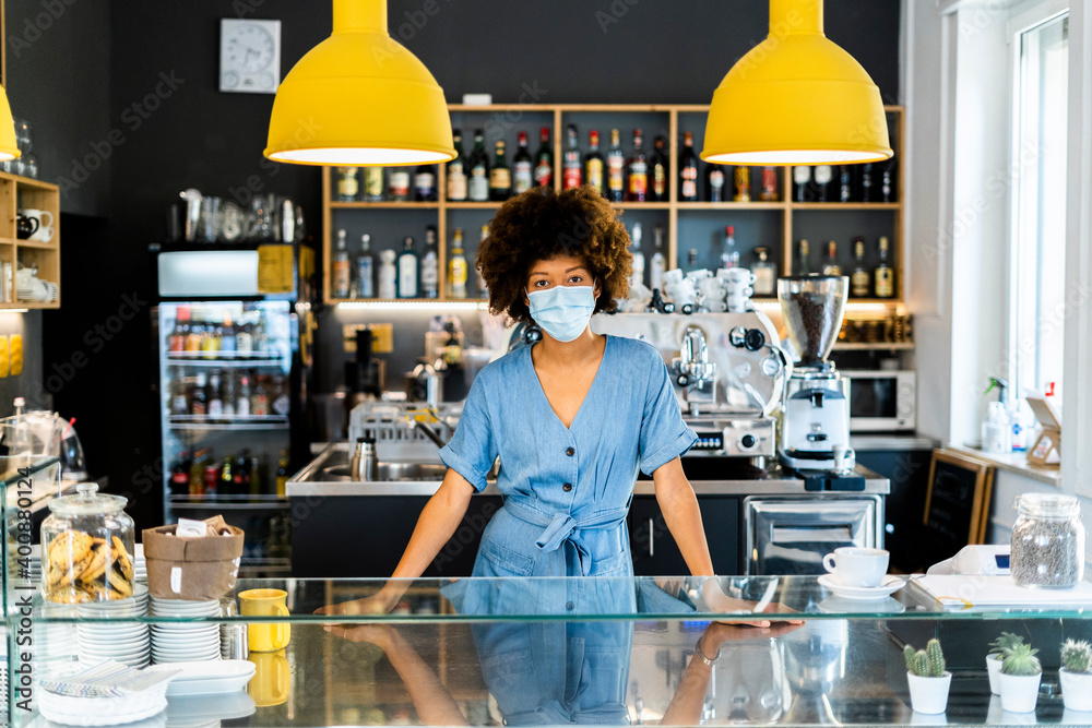 © Giorgio Fochesato/Westend61 - Young female owner wearing mask standing at counter in coffee shop © Giorgio Fochesato/Westend61 - Young female owner wearing mask standing at counter in coffee shop