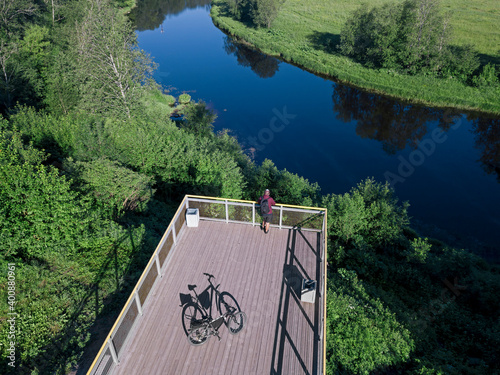 Russia, Leningrad Oblast, Tikhvin, Aerial view of man admiring Tikhvinka river from observation platform photo