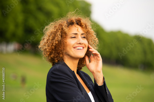 Close-up of smiling businesswoman talking over smart pone while standing outdoors photo