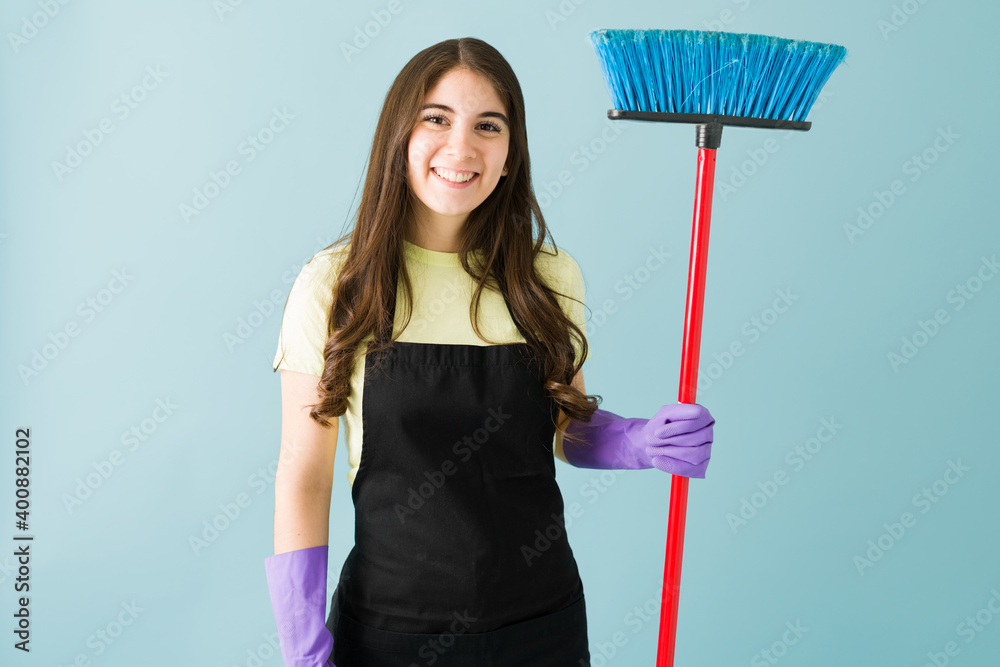 Portrait shot of a caucasian women smiling while holding a broom