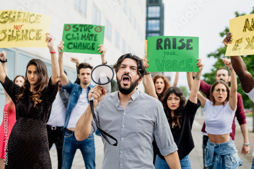 Man shouting through megaphone while protesting with people on street