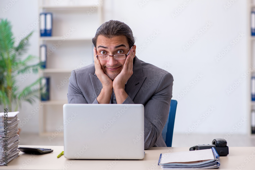 Young male employee unhappy with excessive work in the office Young male employee unhappy with excessive work in the office
