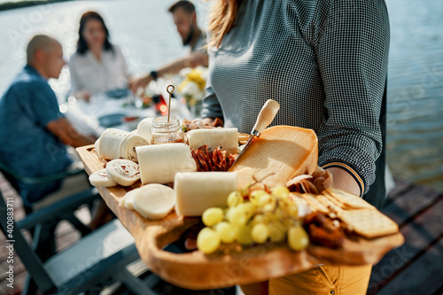 Friends having dinner with a cheese platter at a lake photo