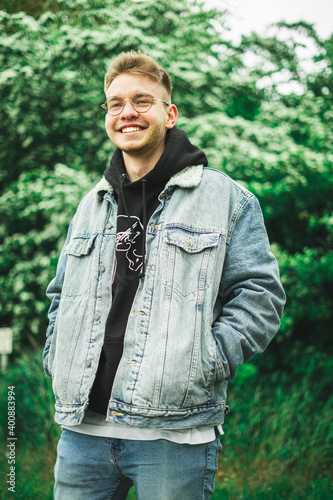 Junger Mann lächelnd vor grünen Sträuchern