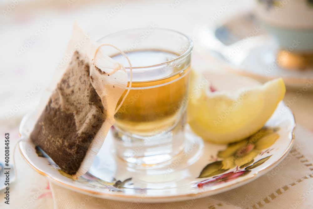 Whiskey in shot glass, slice of lemon and teabag on saucer Whiskey in shot glass, slice of lemon and teabag on saucer