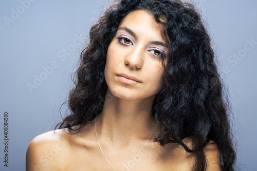 Beautiful brunette girl with long curly hair, studio portrait