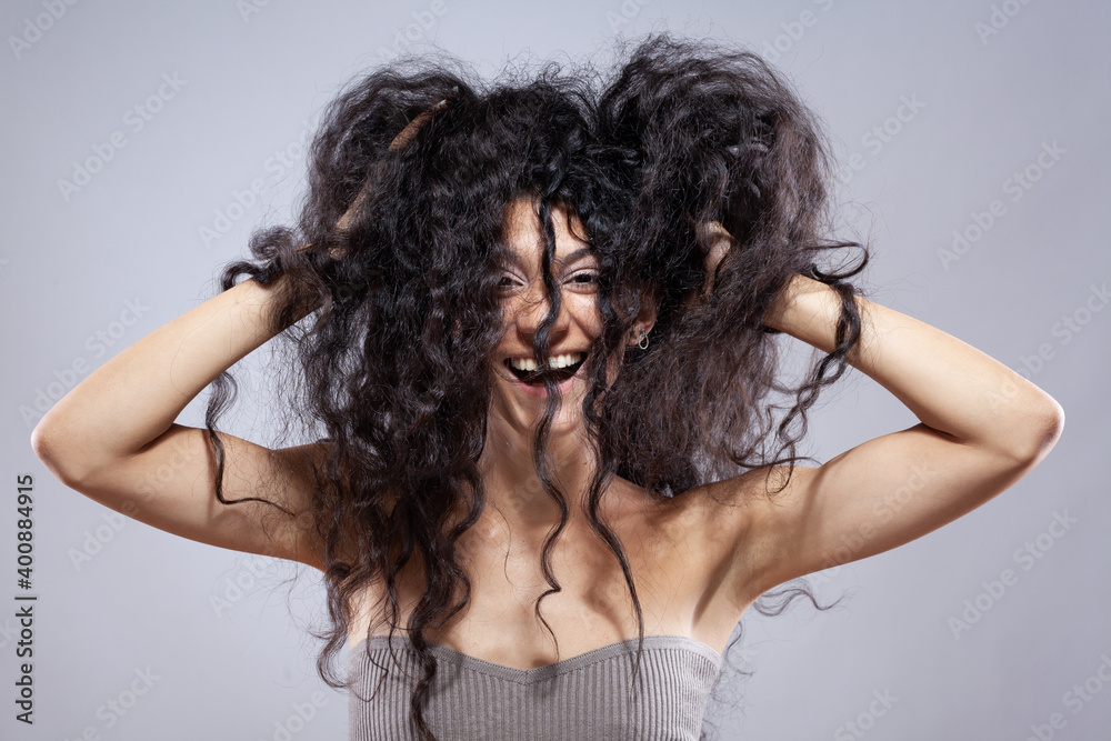 Beautiful brunette girl with long curly hair, studio portrait. Smiling happy face expression Beautiful brunette girl with long curly hair, studio portrait. Smiling happy face expression