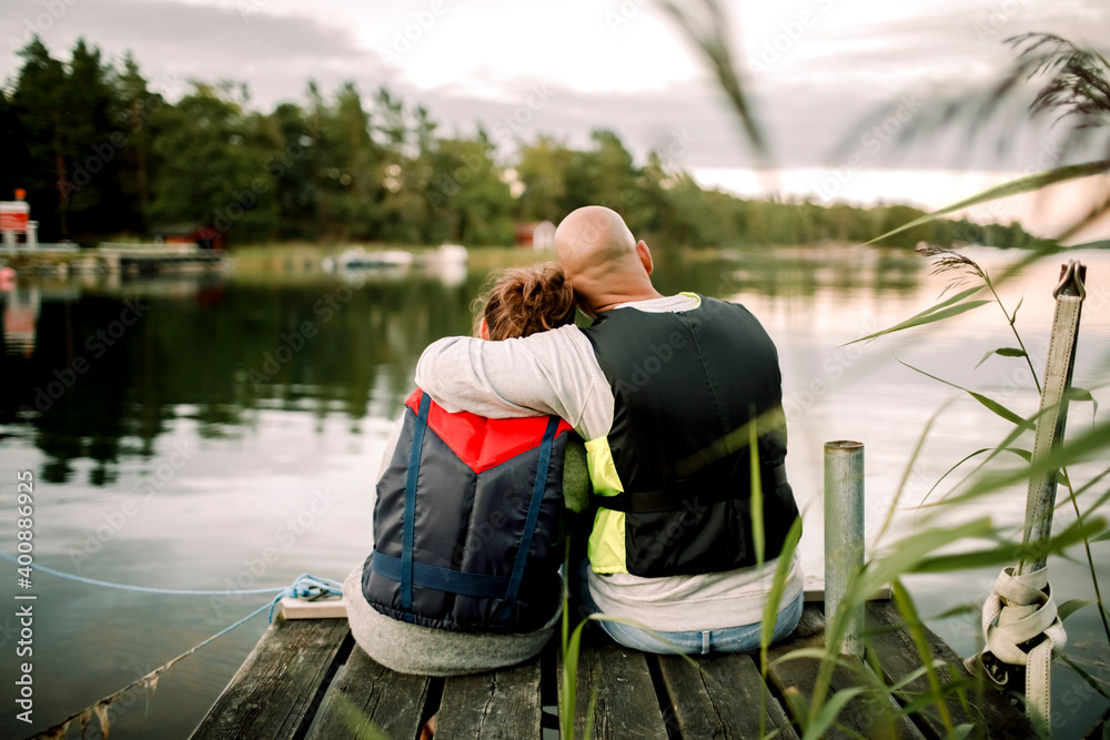 Father and daughter sitting on pier by lake Father and daughter sitting on pier by lake