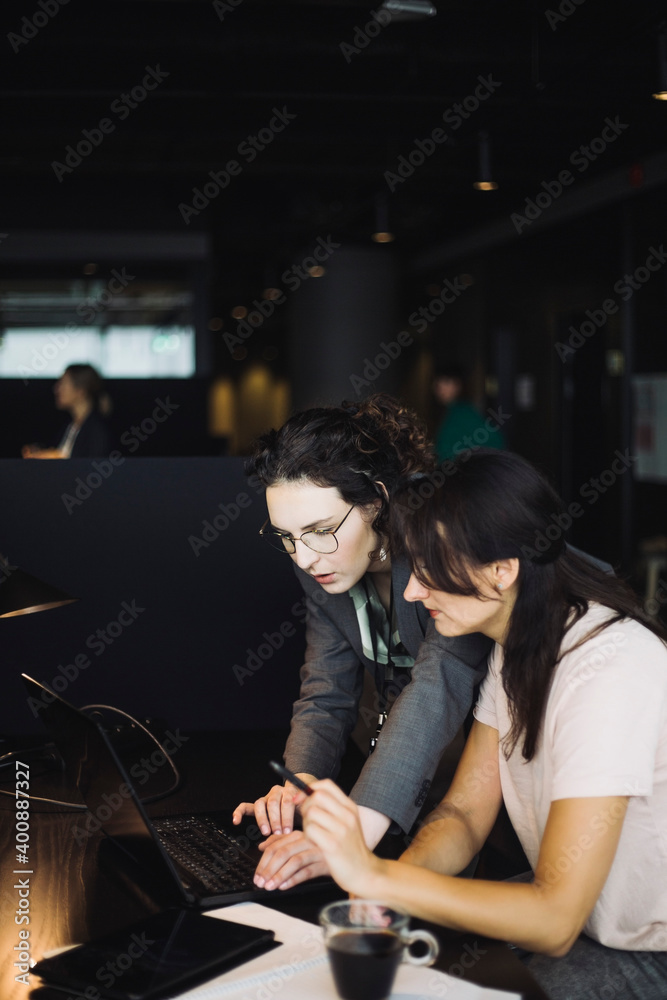 Side view of female professionals working on laptop in office Side view of female professionals working on laptop in office